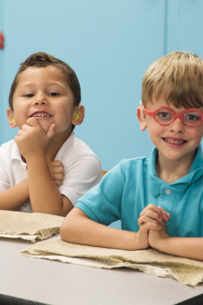 Two preschoolers sitting at a table, smiling.