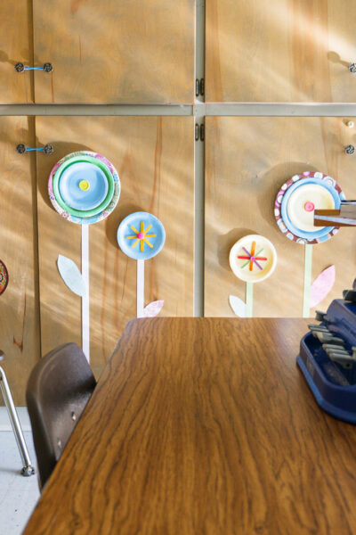 A preschool room with flower art on the wall and a Perkin's Braille Writer on a desk.