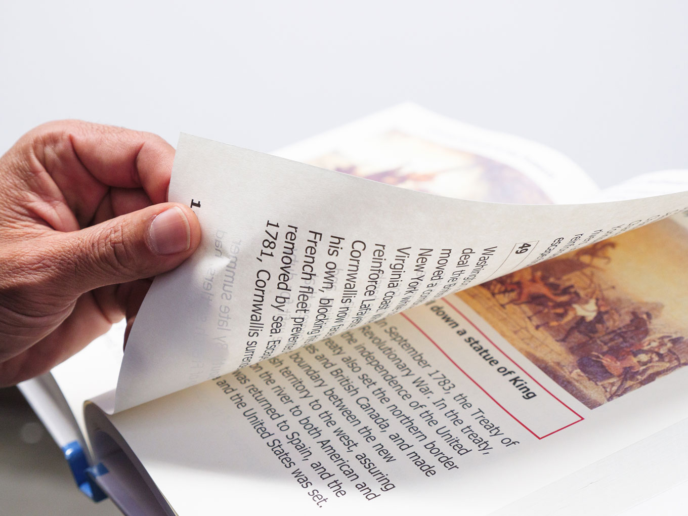 A hand turning the large print page of a book.