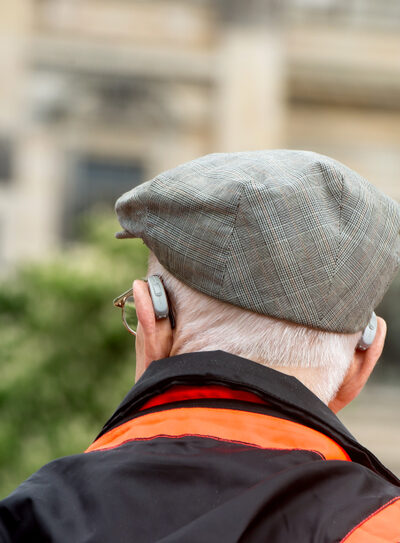 Individual wearing hearing aids walks outdoors