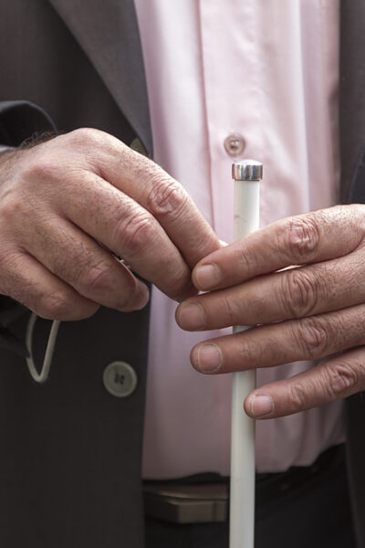 Close-up of hands holding a white cane