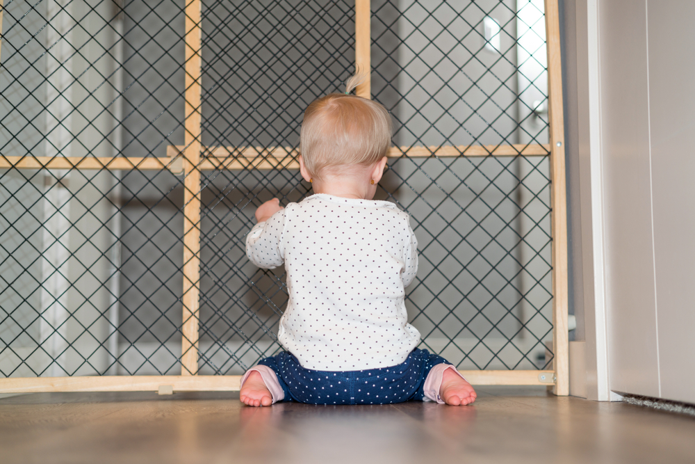 Baby playing behind safety gate.