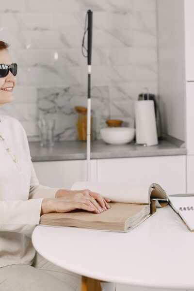 Woman sitting in kitchen reading braille.