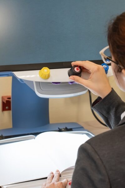 Professionally dressed individual using a video magnifier in an office