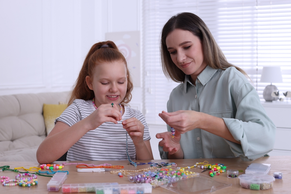 Adult and child making beaded jewelry together