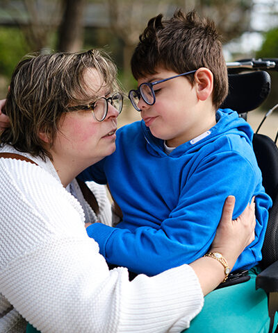boy in a wheelchair and his mother enjoying a day together outdoors in a park