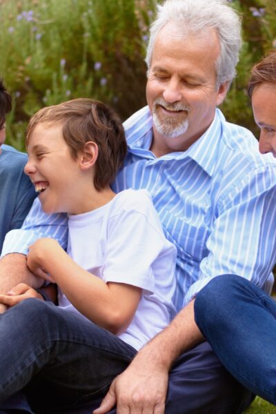 Multigenerational group of men and boys smiling and laughing oudoors.