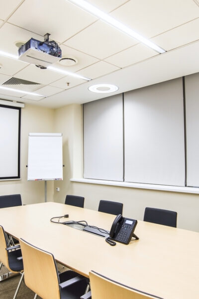 Small empty conference room with TV projector, conference table and chairs.