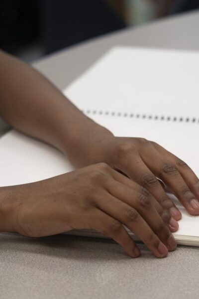 Photo of child's hands reading braille page from book.